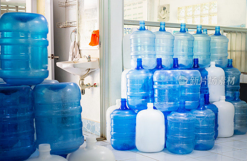 蓝色塑料瓶或蓝色加仑的饮用水堆放在饮用水工厂循环使用饮用水。水厂经营理念