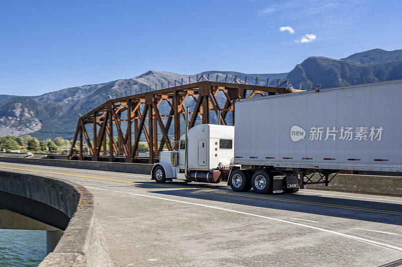 引擎盖经典白色大卡车半挂车牵引车运输货物在干货车半挂车运行在哥伦比亚河峡谷的桥上