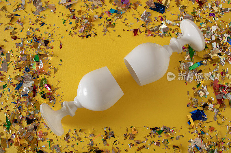 黄色的桌子上撒满了五彩纸屑，还有两个为派对准备的白酒杯