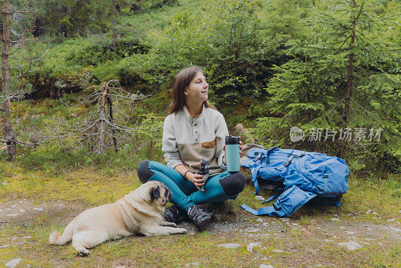 快乐的女子背包客和一只狗在挪威的森林里放松