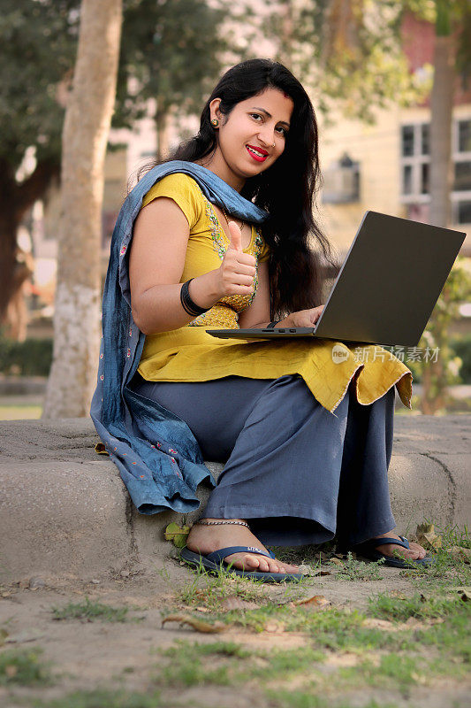 年轻的印度妇女在公园户外使用笔记本电脑