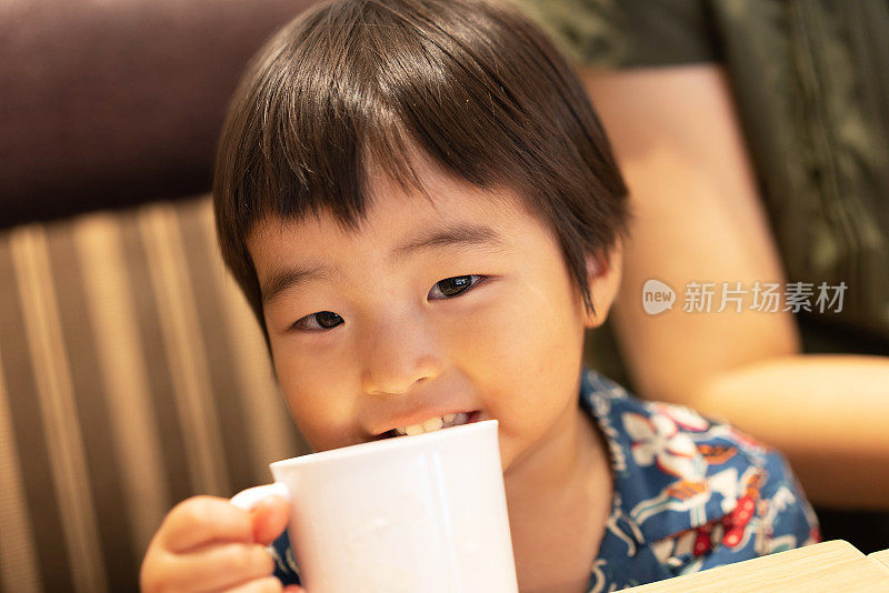 亚洲男孩在旅游目的地的餐厅喝茶