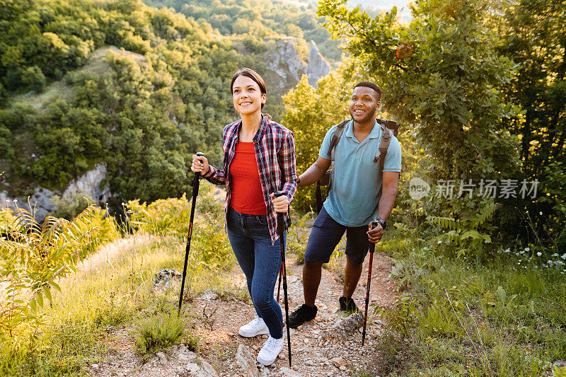 年轻的多种族夫妇在一个阳光明媚的日子里在山上徒步旅行