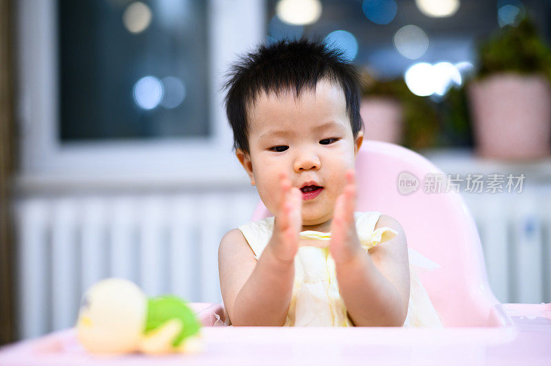 亚洲可爱的小婴儿坐在餐厅的婴儿餐椅上