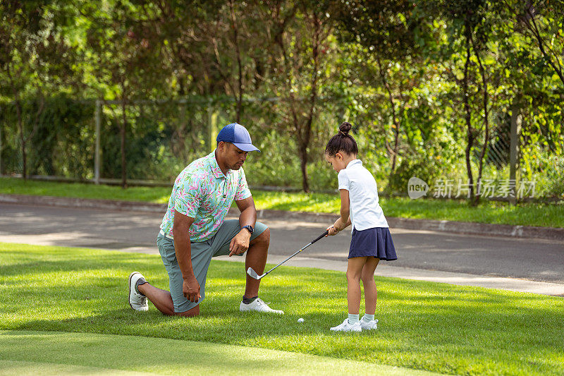 慈爱的父亲教女儿如何挥动高尔夫球杆