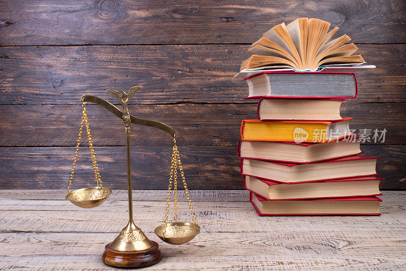 法律概念-打开法律书，天平放在法庭或执法办公室的桌子上。