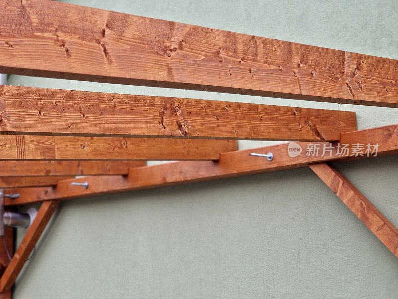 房屋旁边的木制藤架使用螺纹杆和螺钉固定在房屋的墙壁上，直接连接到立面。定制的木工工作。广告预告片