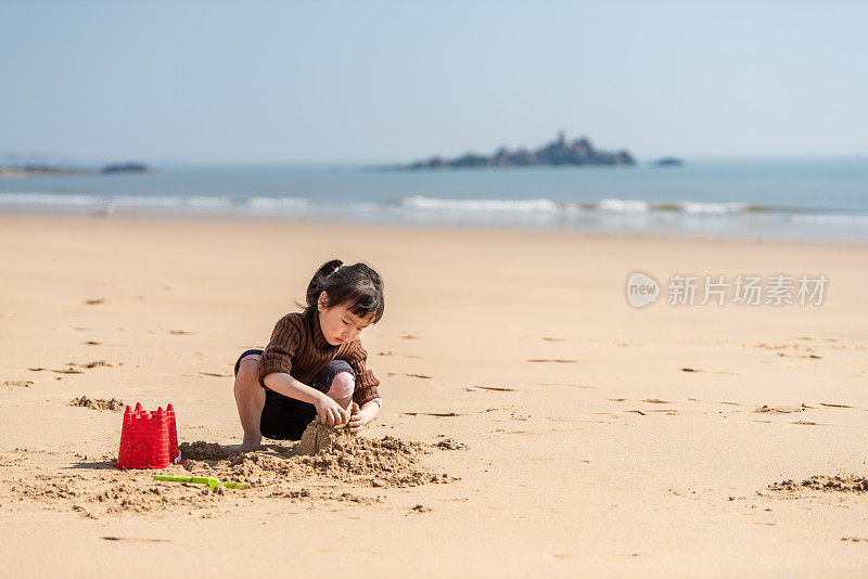 一个中国小女孩在沙滩上玩沙子