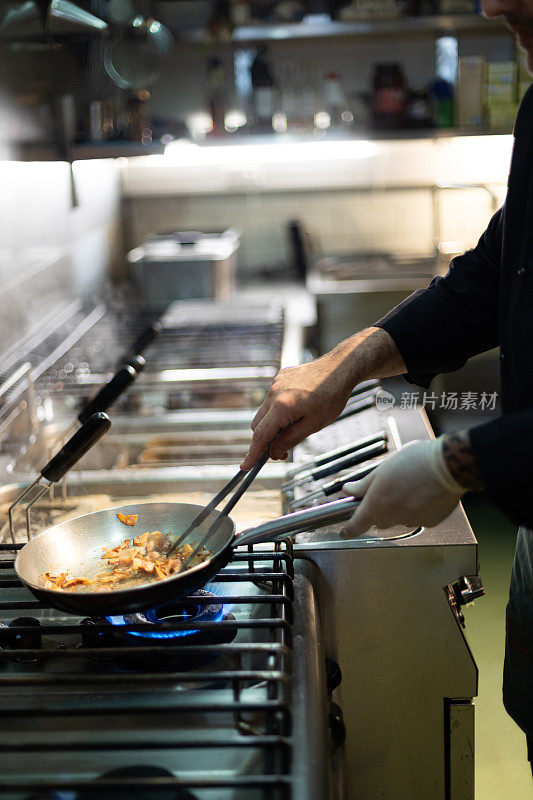 厨师在餐厅用煎锅烹饪意大利面