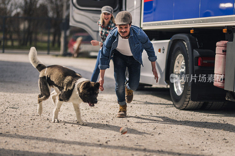 一对卡车司机夫妇在旅途中休息一下，和他们的狗一起玩