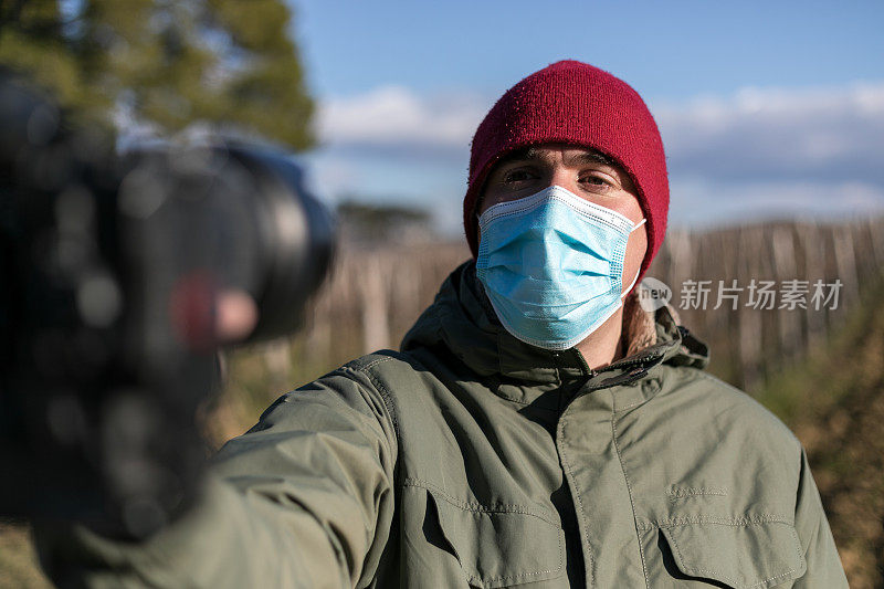 戴着面具在公园拍视频的男人