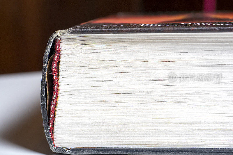 特写的一部分，一本厚厚的厚厚的书在一个白色的表面学习和知识的概念。
