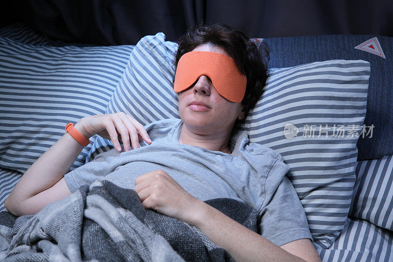 成熟的女人睡在床上用眼罩