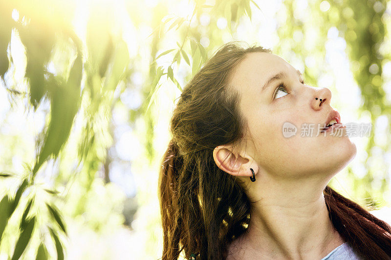 一位美丽的年轻女子从一棵柳树下抬头望着，也许是在寻求精神上的灵感