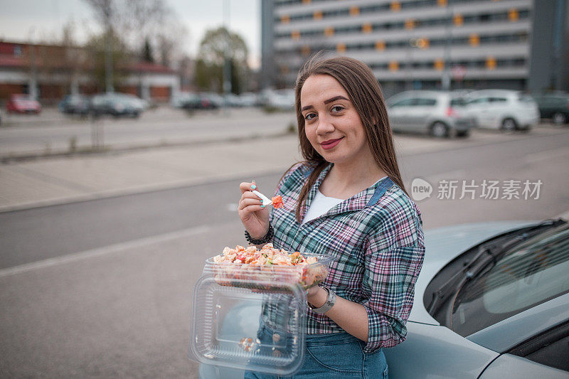 美女吃着塑料盒里的沙拉