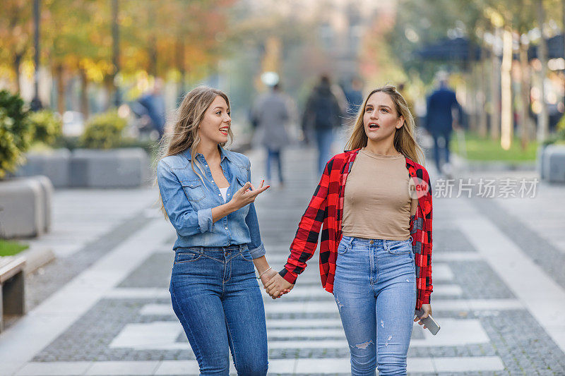 两个年轻的女人走在市区，享受着友谊。