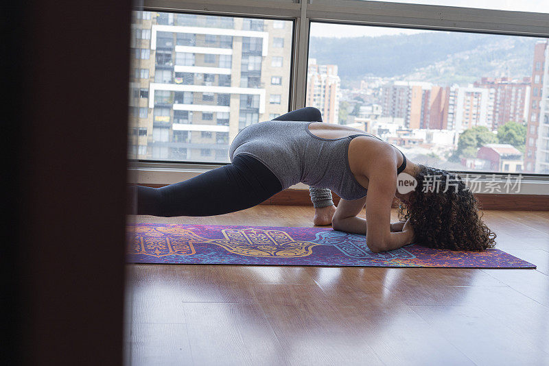 一个拉丁女人正在她的公寓里做瑜伽练习