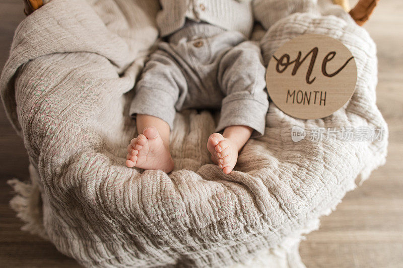 一个月大的男孩的脚趾，有12个脚趾“多指”躺在一个舒适的薄纱棉毯子在摩西篮子里