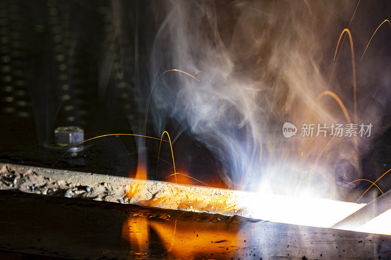 宏观焊条焊接在钢凹处，具有明亮的白光、橙色火焰、烟雾和电弧火花