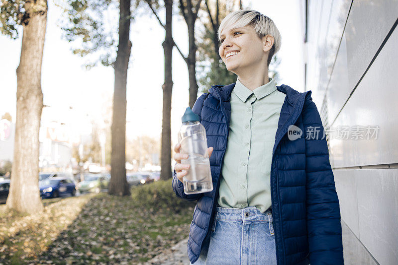 一个快乐的年轻女子的肖像行走和携带水瓶