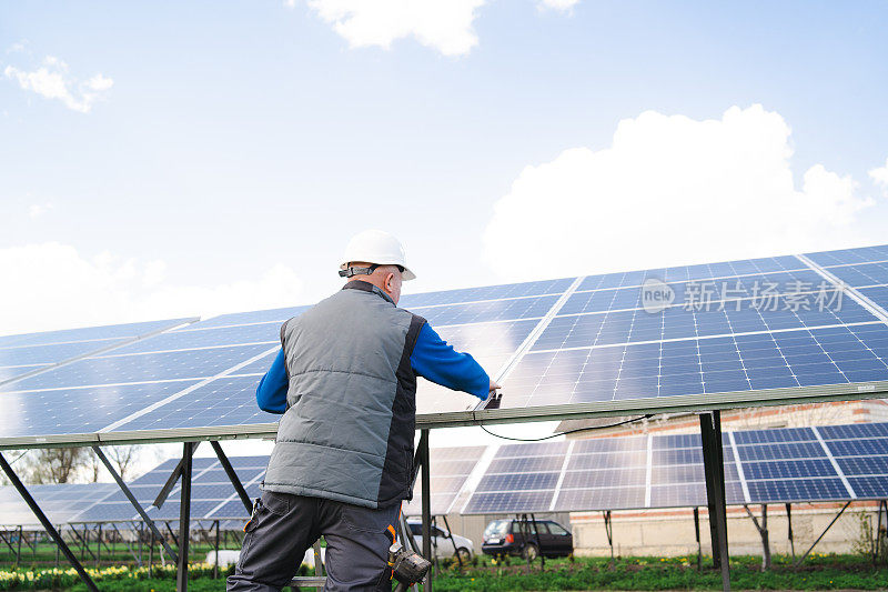 太阳能电池板和蓝天。站在太阳能电池板附近的男子
