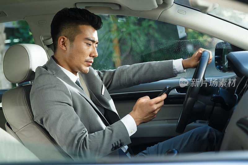 青年男人开车看手机