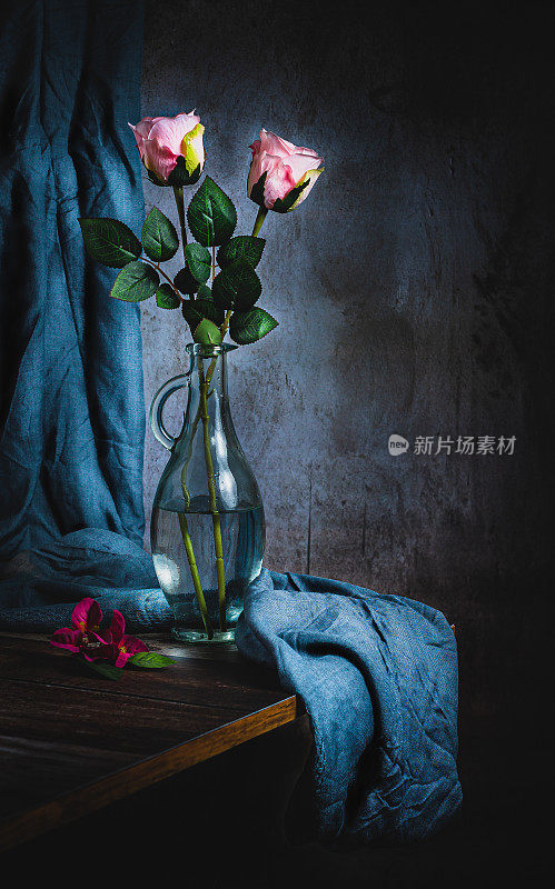 玻璃花瓶的静物，各种颜色的玫瑰和灰色的背景，有复制的空间。