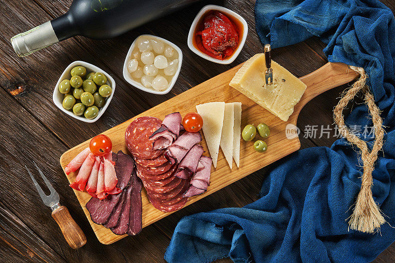 在一张质朴的木桌上，可以看到由奶酪、腌火腿、意大利腊肠葡萄酒和西班牙香肠组成的小吃