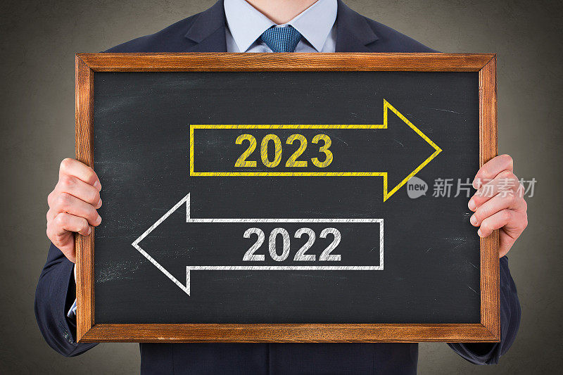 商人在黑板背景上画旧年或2023年