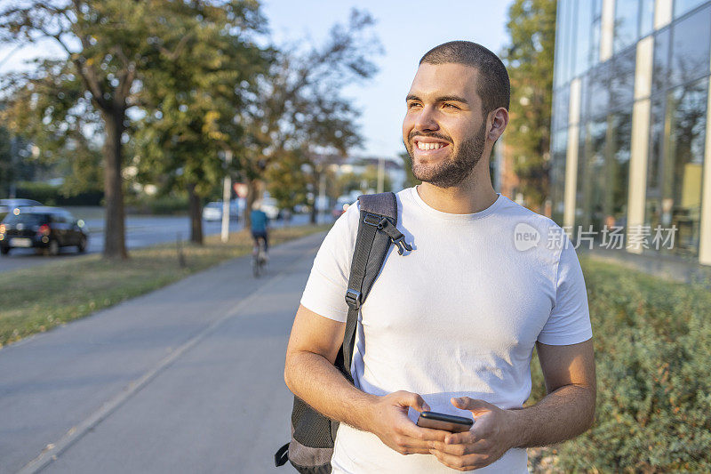 年轻的男学生微笑着走过他的学院