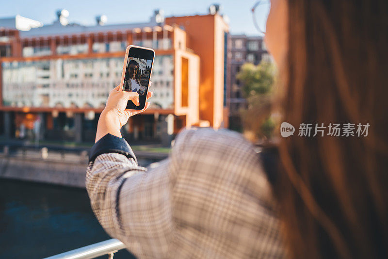 女性旅行者使用智能手机摄像头在社交网络上拍摄在线视频，微笑的女性在城市旅行中使用4G连接进行facetime通话