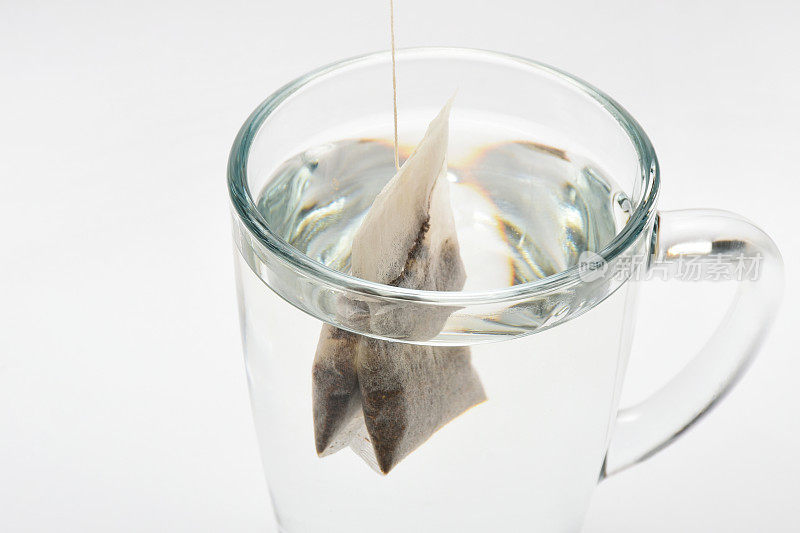 将茶包放入热水中。茶包在一个透明的茶杯在白色的背景
