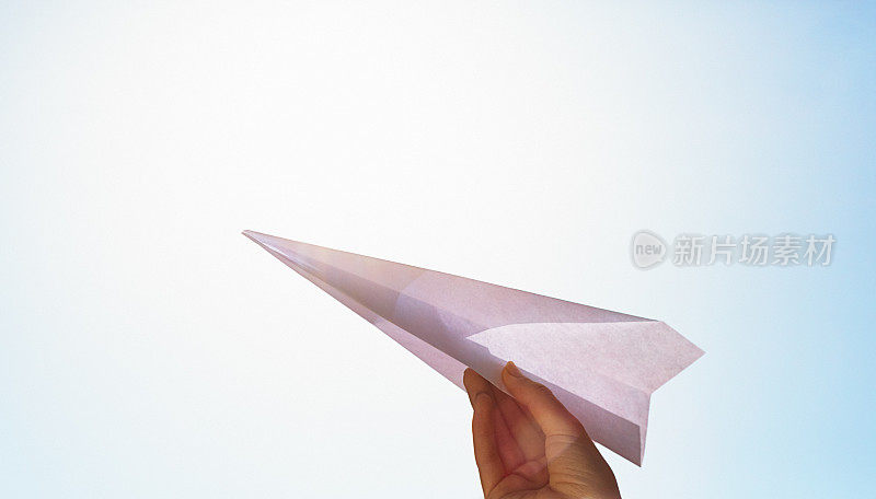 在炎炎烈日下，十几岁女孩的手正准备向晴朗的夏日天空发射纸飞机