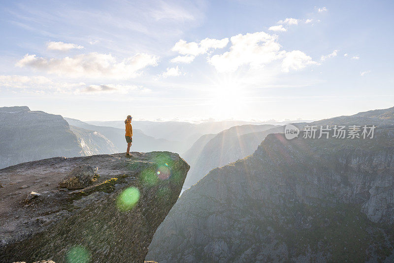 一名女徒步旅行者站在巨魔之舌(trollltunga)著名的岩石上，俯瞰湖面上的山谷全景，是挪威著名的探险之旅