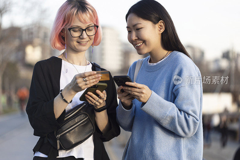 两个快乐的女人用智能手机和信用卡在网上购物