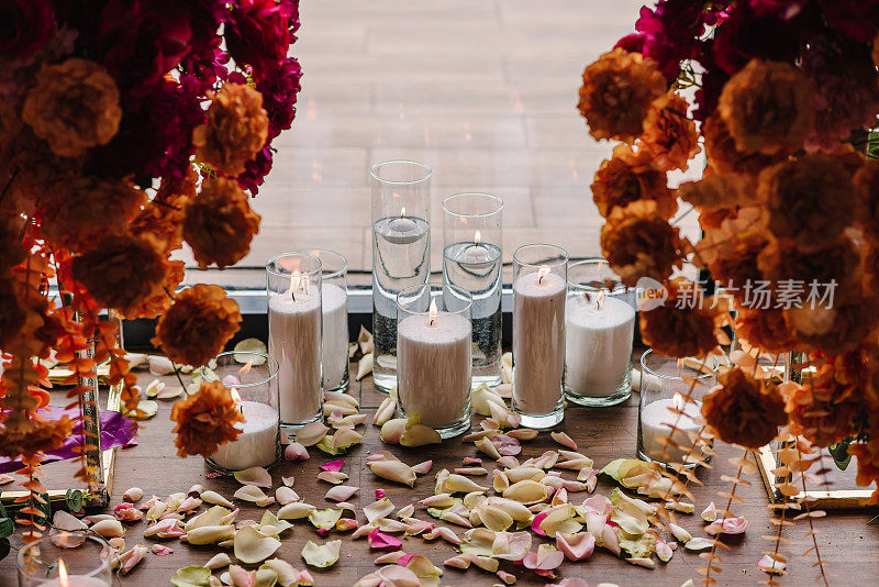 蜡烛，地上的玫瑰花瓣。特写装饰细节。照片墙与码头，拱门装饰粉红色，橙色的鲜花为宴会区，大厅的生日聚会。豪华婚礼的婚宴。