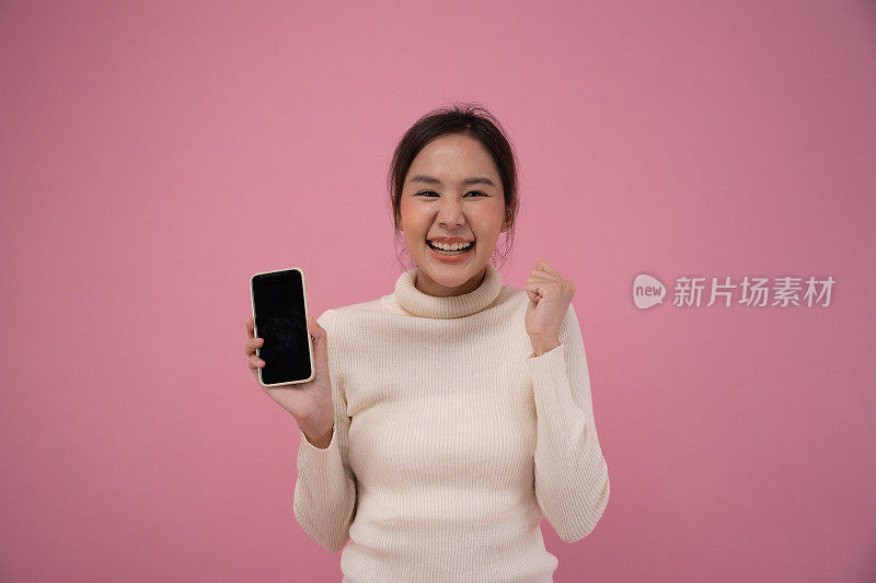惊讶的表情，哇。快乐的亚洲女性对智能手机的成功感到兴奋。屏幕显示在移动显示成功，奖励，奖金，获得促销，获胜者，获胜，折扣购物。肖像