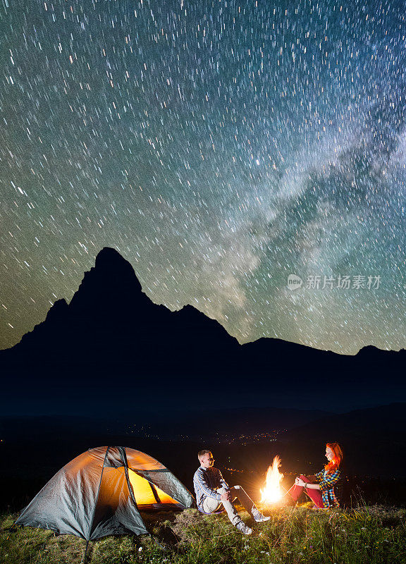 旅游家庭坐在篝火下，在难以置信的美丽星空下