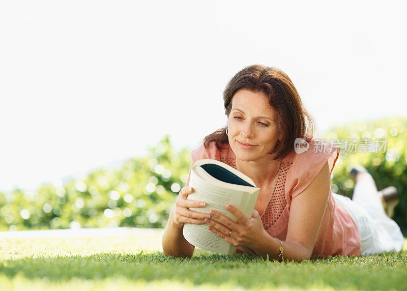 悠闲成熟的女人在草坪上看书