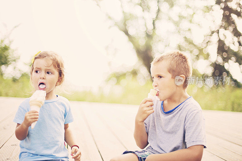 男孩和女孩在户外吃冰淇淋在散景的背景