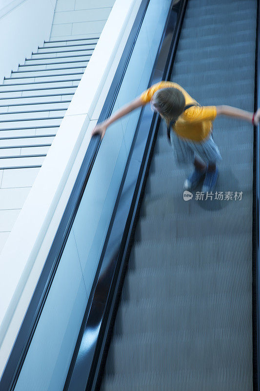 在自动扶梯上的男性青少年，高架的视野，模糊的运动