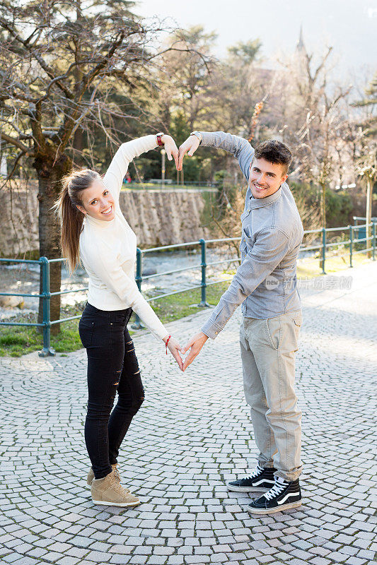 幸福的年轻夫妇形成心形的手臂
