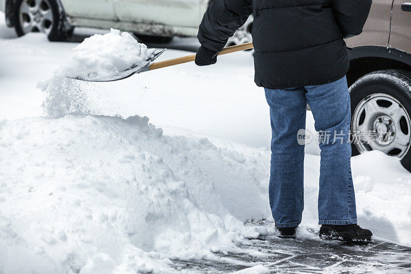 用雪铲从人行道上扔雪的人