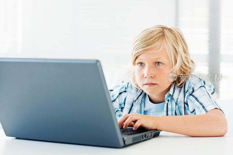 天真可爱的小男孩在用笔记本电脑