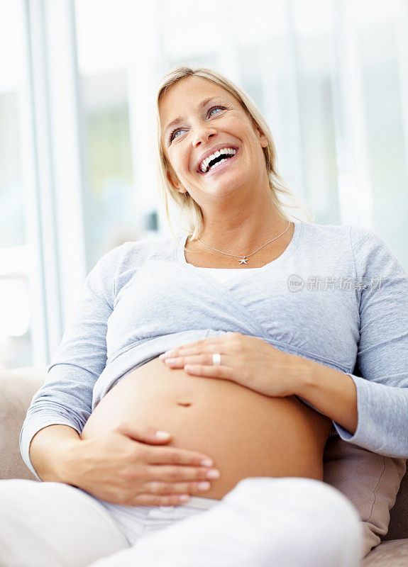 漂亮的孕妇抱着她的肚子微笑