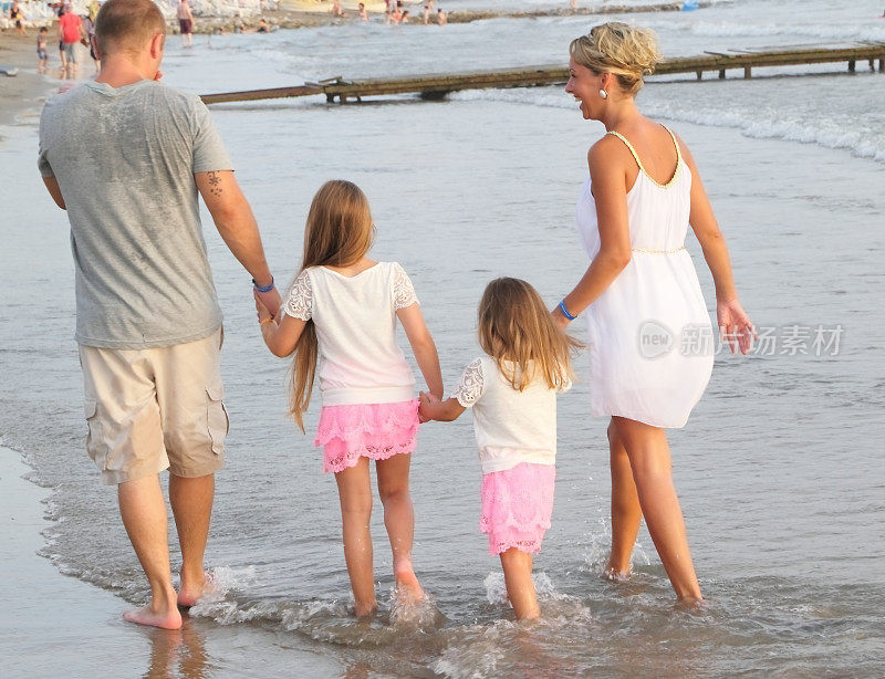 幸福的一家人在海滩上散步