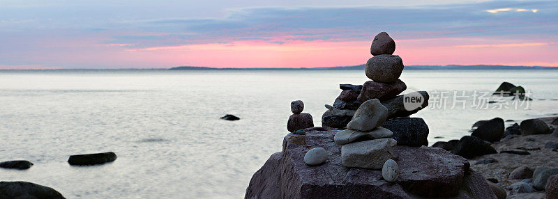 日落时，在沙滩上用巨石平衡石头