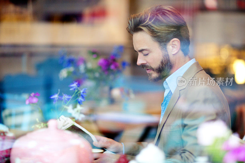 一个年轻英俊的男人正在咖啡馆里看报纸