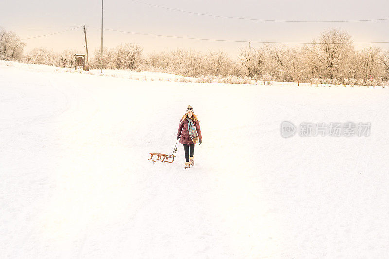 雪地里拉着雪橇的漂亮女孩