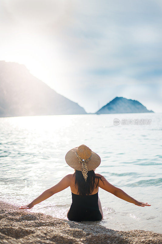 沉思的女孩在大海和夕阳的背景